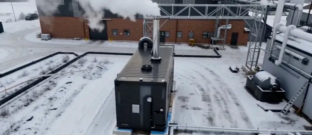 A hybrid boiler container seen from above on a snowy factory site, with steam rising